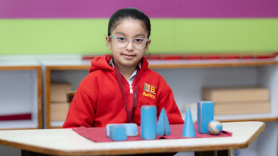 Young girl in red sweater explores geometric shapes in a Montessori classroom setting.